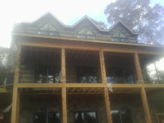 Dormers and porch framing on a large log home under construction — Roof Coating work by our crew in Lake City